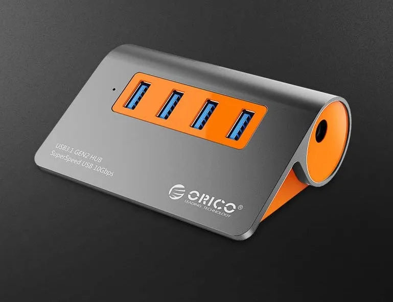 Dark grey aluminium USB hub with orange accents showing four USB 3.1 ports and separate data cable