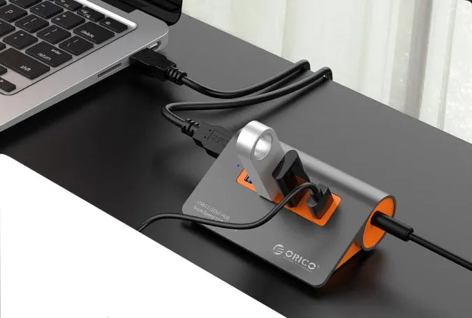 Dark grey aluminium USB hub with orange accents showing four USB 3.1 ports and separate data cable