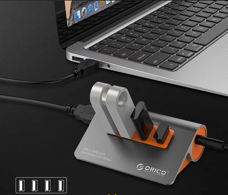 Dark grey aluminium USB hub with orange accents showing four USB 3.1 ports and separate data cable
