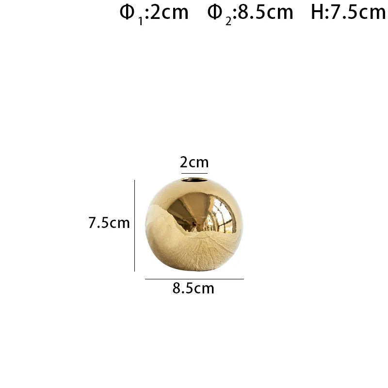 Handmade spherical ceramic vase with electroplated gold finish on a table