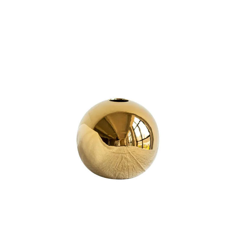 Handmade spherical ceramic vase with electroplated gold finish on a table