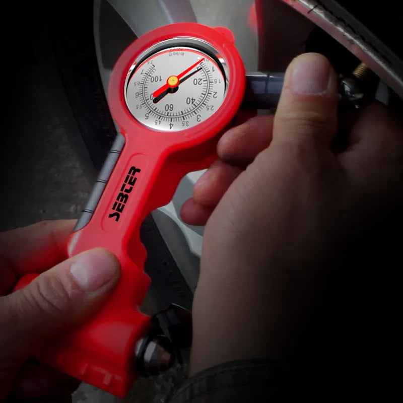Red portable car tyre pressure gauge with integrated safety hammer, seat belt cutter, and snow shovel on a white background
