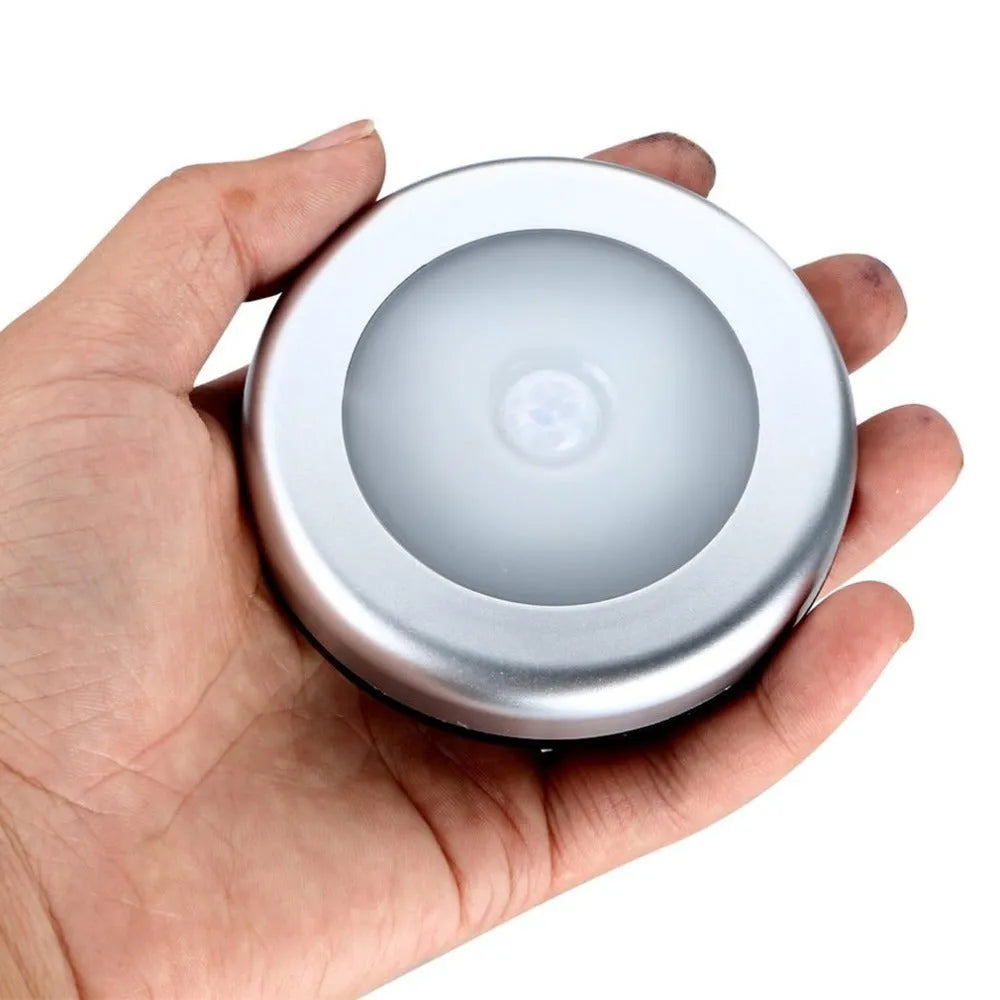 Silver circular battery-powered motion sensor night light with a white PC plastic lampshade.