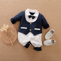 Baby boy wearing a long-sleeved gentleman-style cotton romper in a neutral colour.