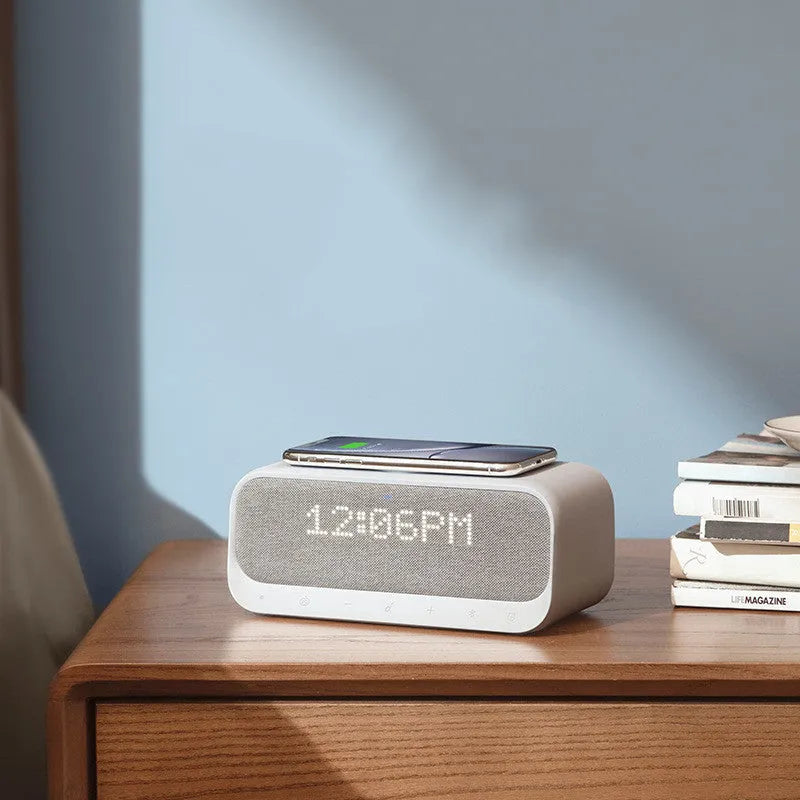 White Anker Soundcore Bluetooth speaker with wireless charging dock and digital alarm clock display.