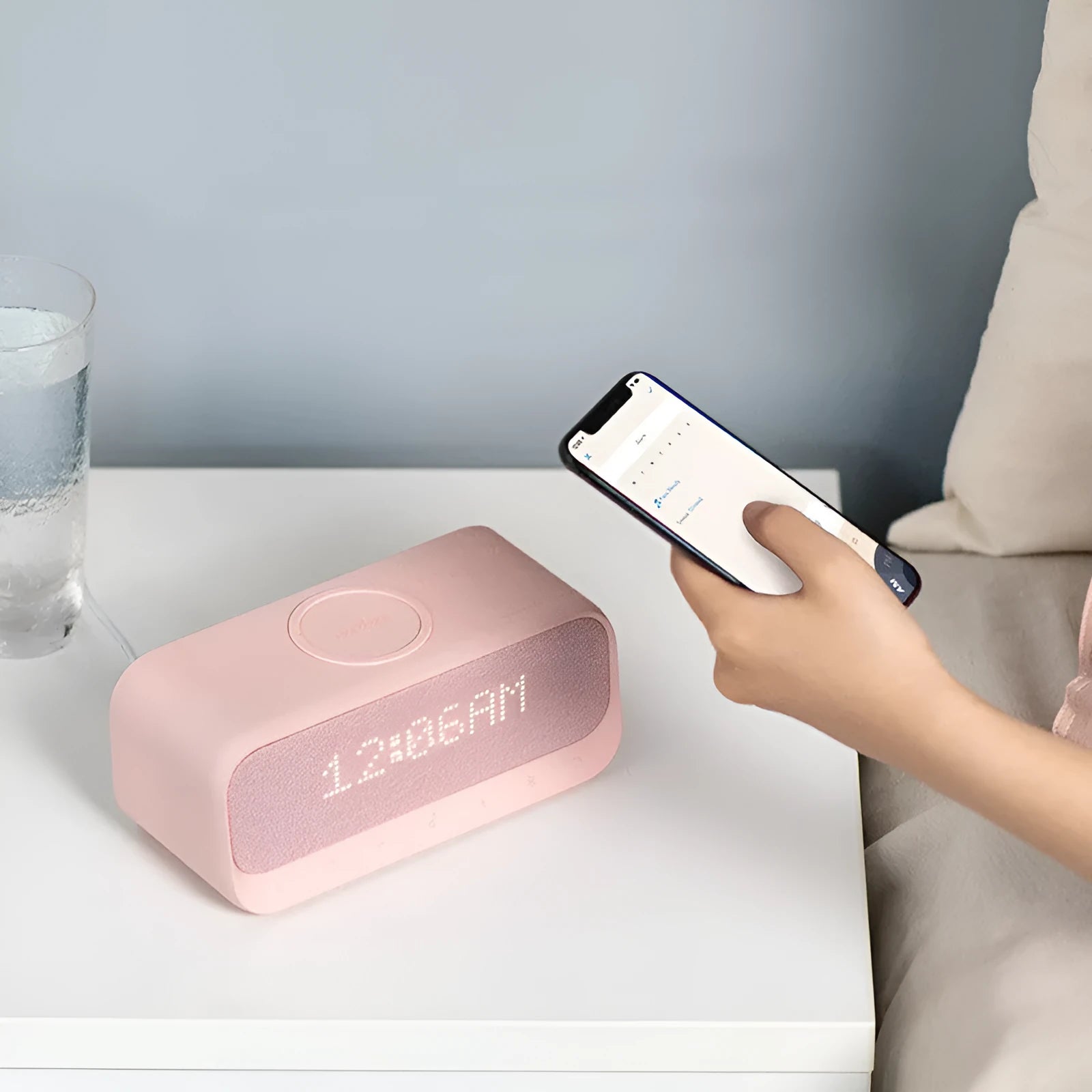 White Anker Soundcore Bluetooth speaker with wireless charging dock and digital alarm clock display.