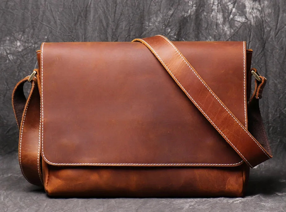 Brown vintage leather men's messenger bag with a shoulder strap showing internal organiser pockets.
