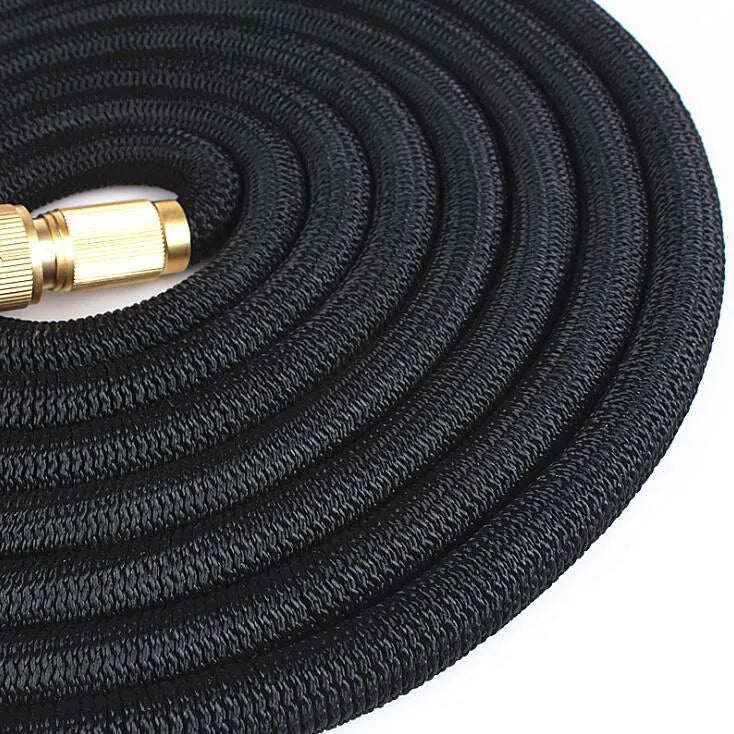 Expandable magic flexible water hose in black laid on grass showing compact initial length and stretched working length