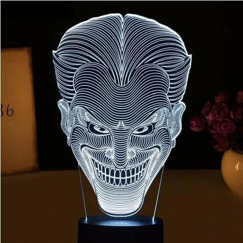 3D acrylic LED lamp displaying coloured light on a desk, with a remote control and USB cable