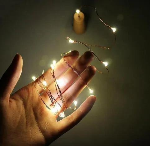 Silver copper wire LED string light with bottle stopper for decorative lighting.