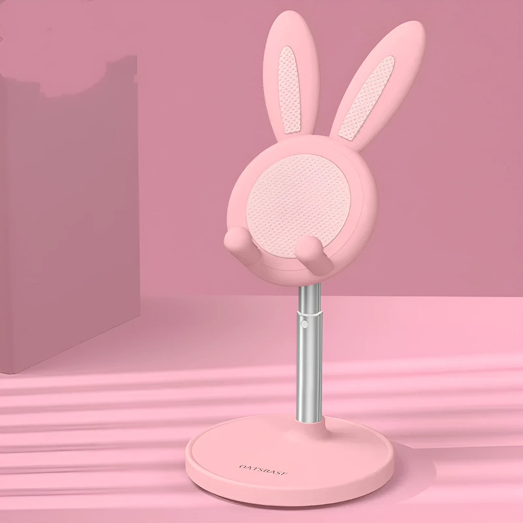 Silicone rabbit phone stand in pink on a desk holding a smartphone at an adjustable angle