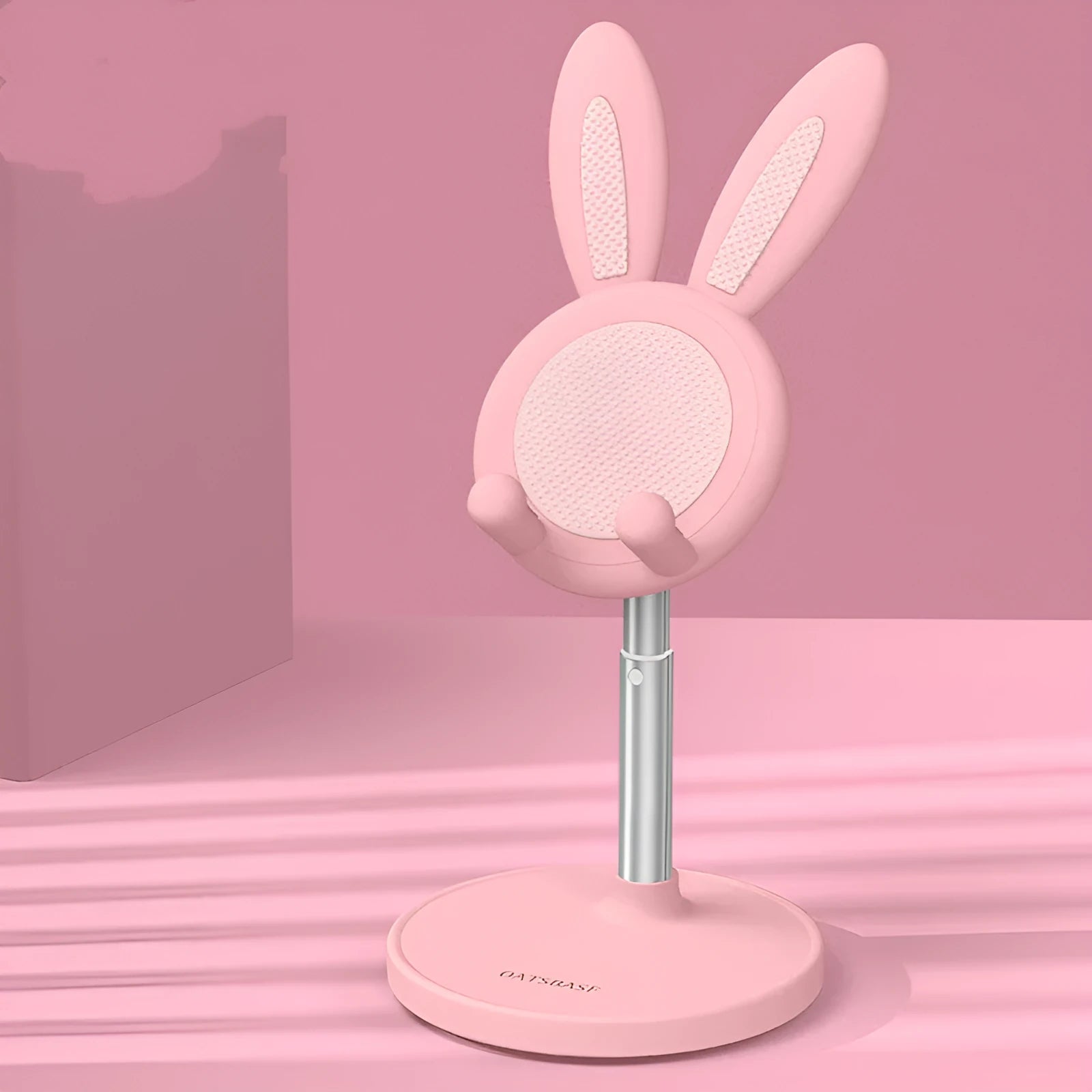 Silicone rabbit phone stand in pink on a desk holding a smartphone at an adjustable angle