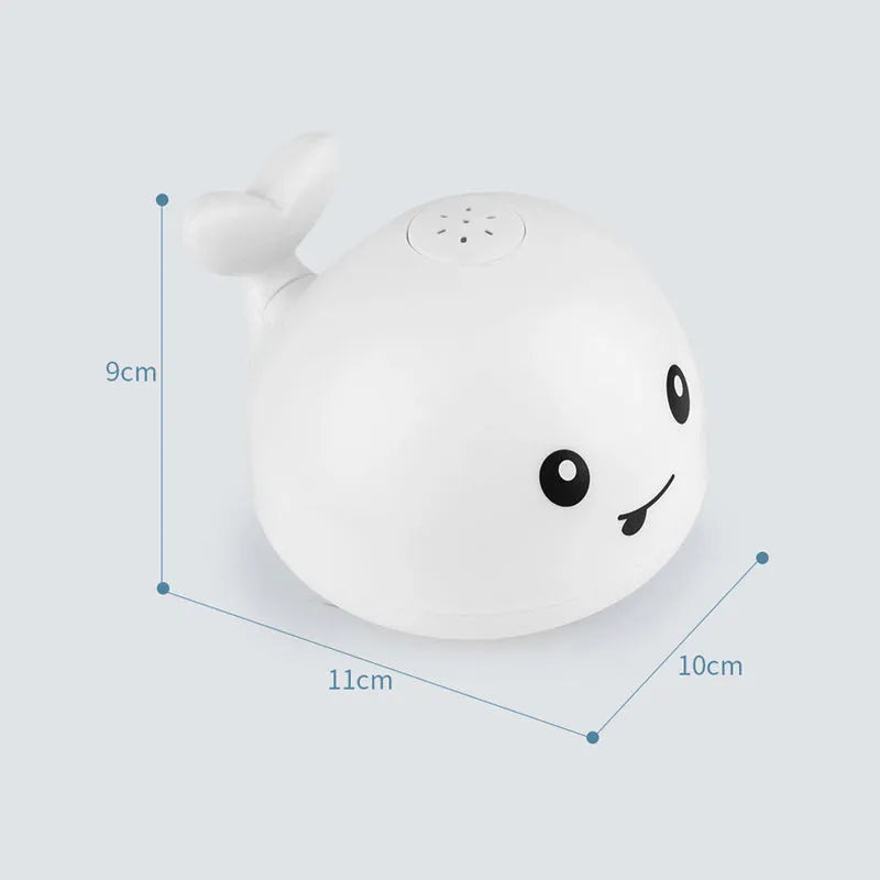 Automatic electric whale bath toy spraying water with LED lights on, floating in a baby bath.