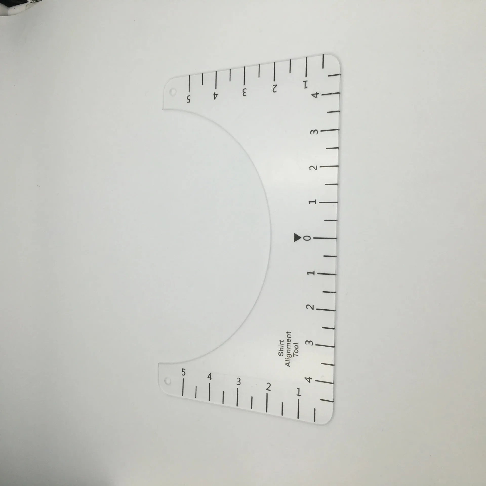 Transparent acrylic sewing ruler for aligning T-shirt designs, measuring 10 by 6 inches.