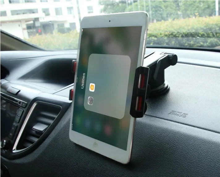 Black universal tablet PC car stand bracket clamped to dashboard centre console holding a tablet
