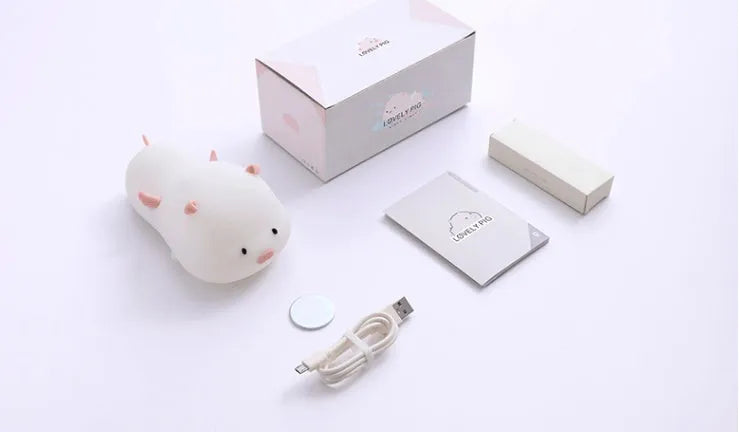 Pink silicone pig-shaped night light with touch control on bedside table
