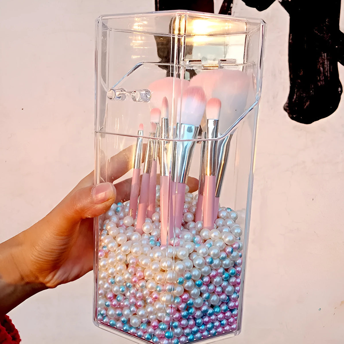 Clear acrylic makeup brush holder on a countertop with pearl coloured beads inside, measuring 12.3x10.6x21.5cm