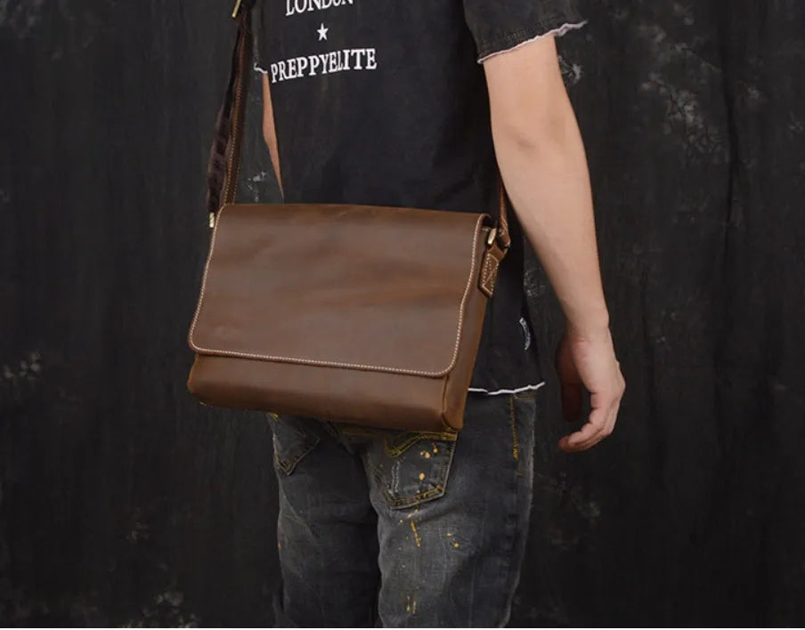 Brown vintage leather men's messenger bag with a shoulder strap showing internal organiser pockets.