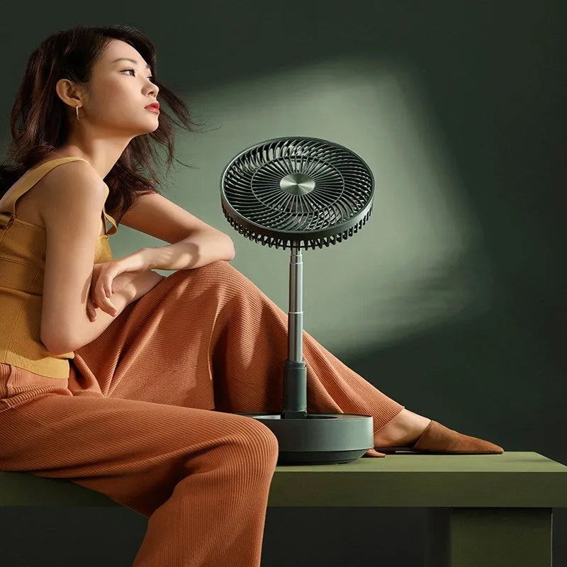 Green telescopic floor fan extended to full height with remote control resting beside base