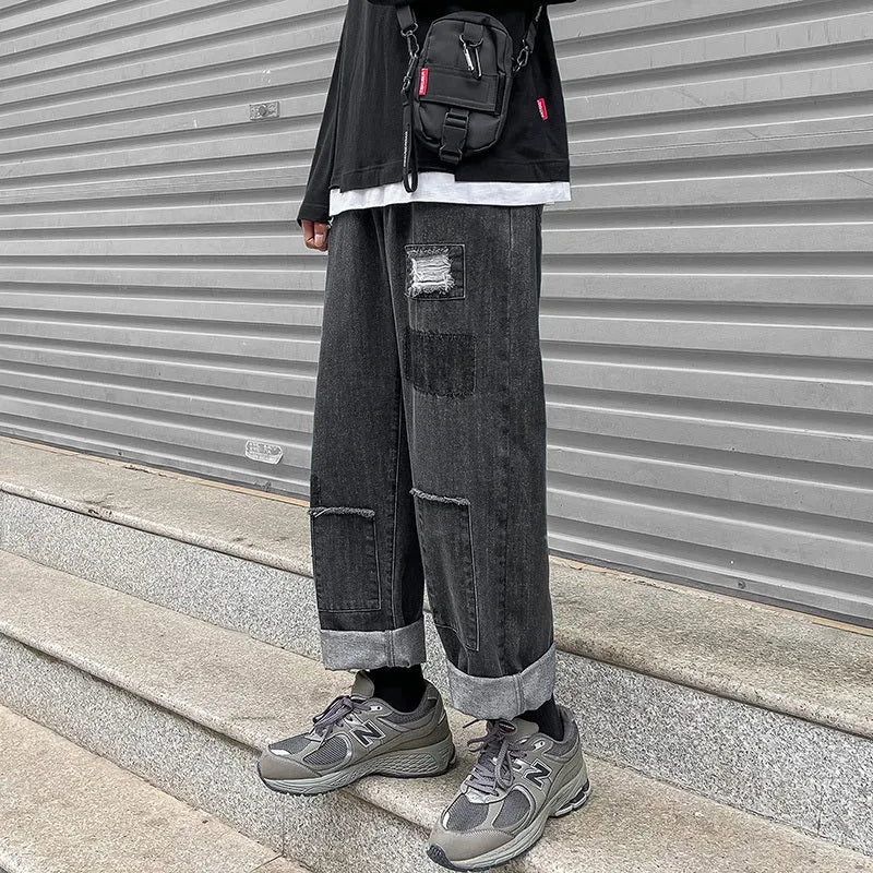 Men's high street ripped jeans with loose straight leg fit in black, showing rips on front thigh area