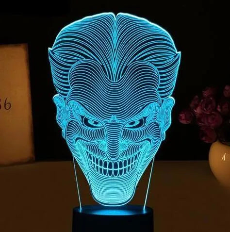 3D acrylic LED lamp displaying coloured light on a desk, with a remote control and USB cable