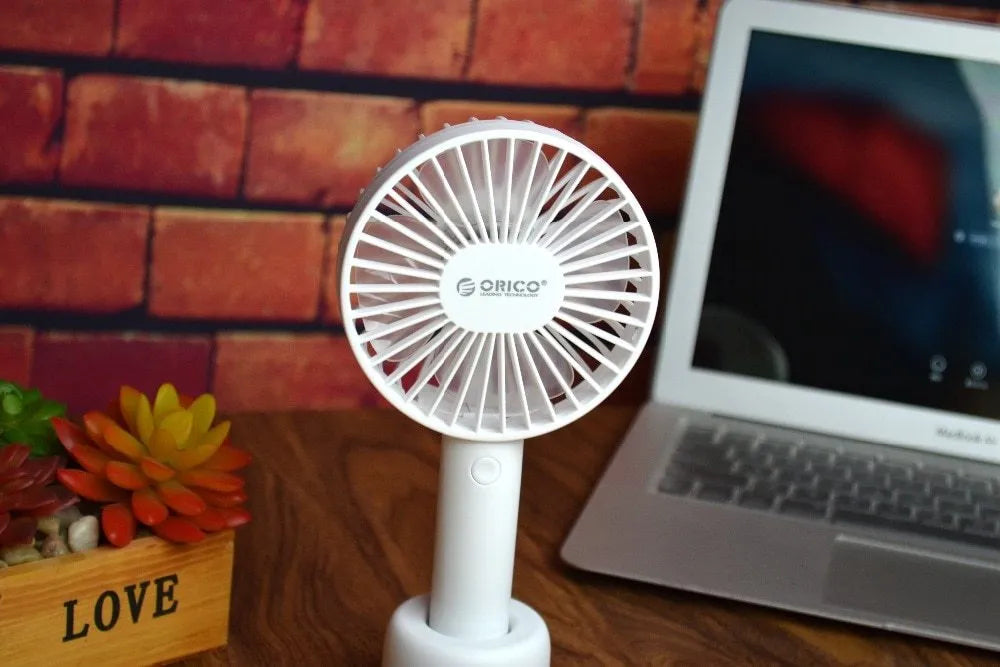 White ORICO FH1 USB rechargeable desk fan with fine-line texture on a desk, showing compact size.