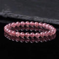 A women's bracelet with round, polished strawberry quartz crystal beads in pinkish-red tones.