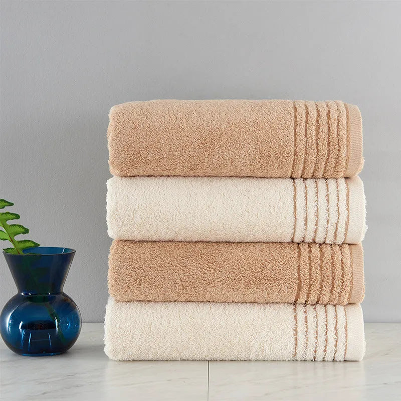 Beige and brown cotton towel set showing three sizes: square face cloth, hand towel, and bath towel.