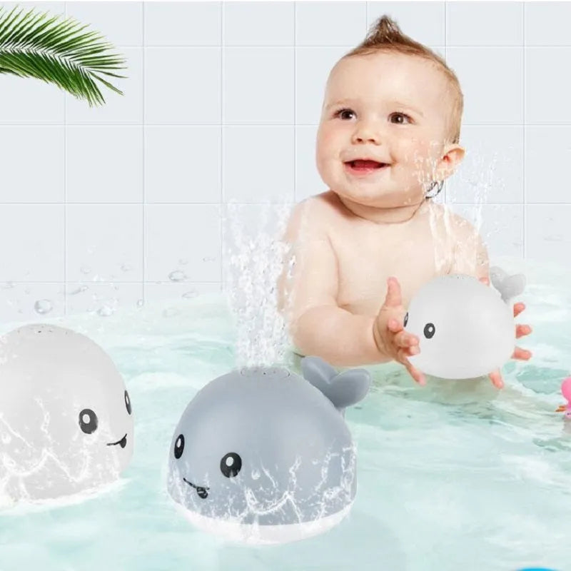 Automatic electric whale bath toy spraying water with LED lights on, floating in a baby bath.
