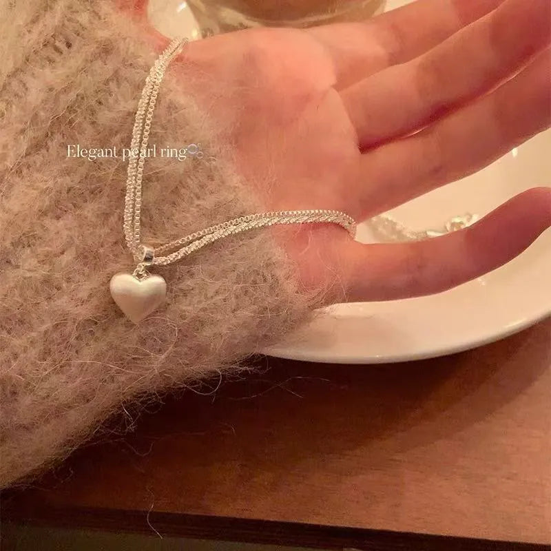 Double-layer brushed heart pendant necklace on model showing adjustable chain length