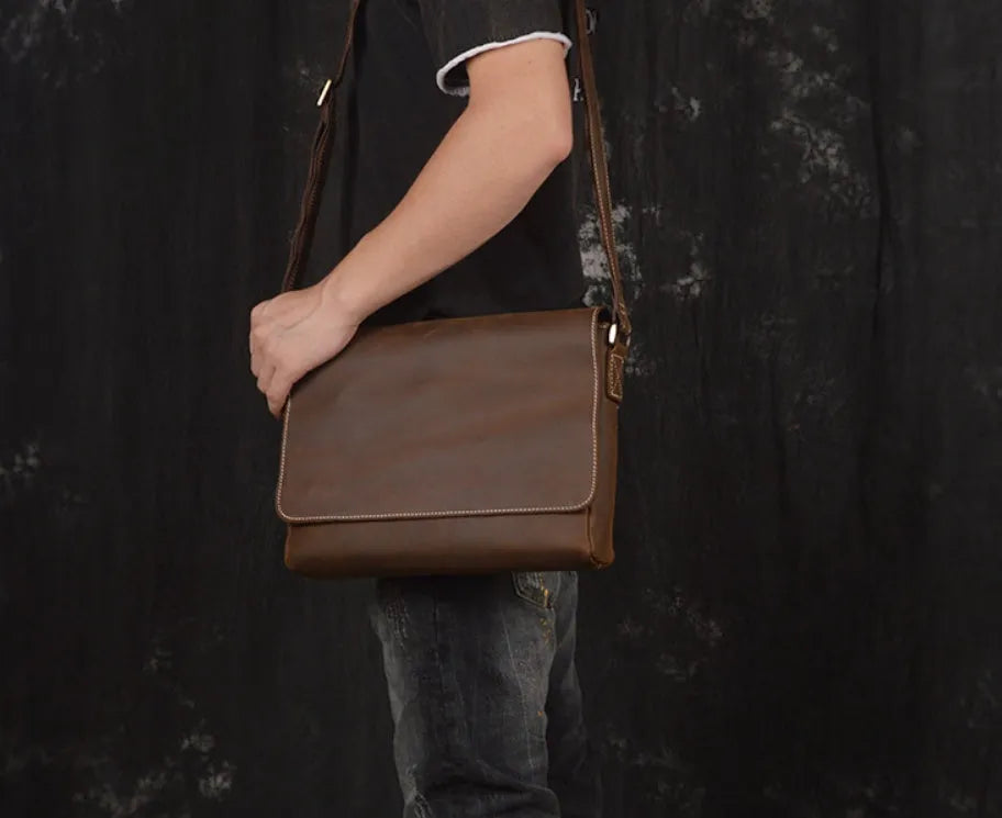 Brown vintage leather men's messenger bag with a shoulder strap showing internal organiser pockets.