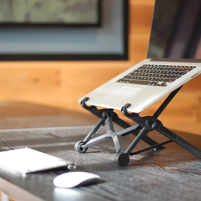 Black reinforced nylon folding laptop stand shown open in use and collapsed for storage.