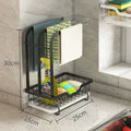 Foldable white plastic kitchen rack for wall mounting or desktop use, holding a sponge and cloth.