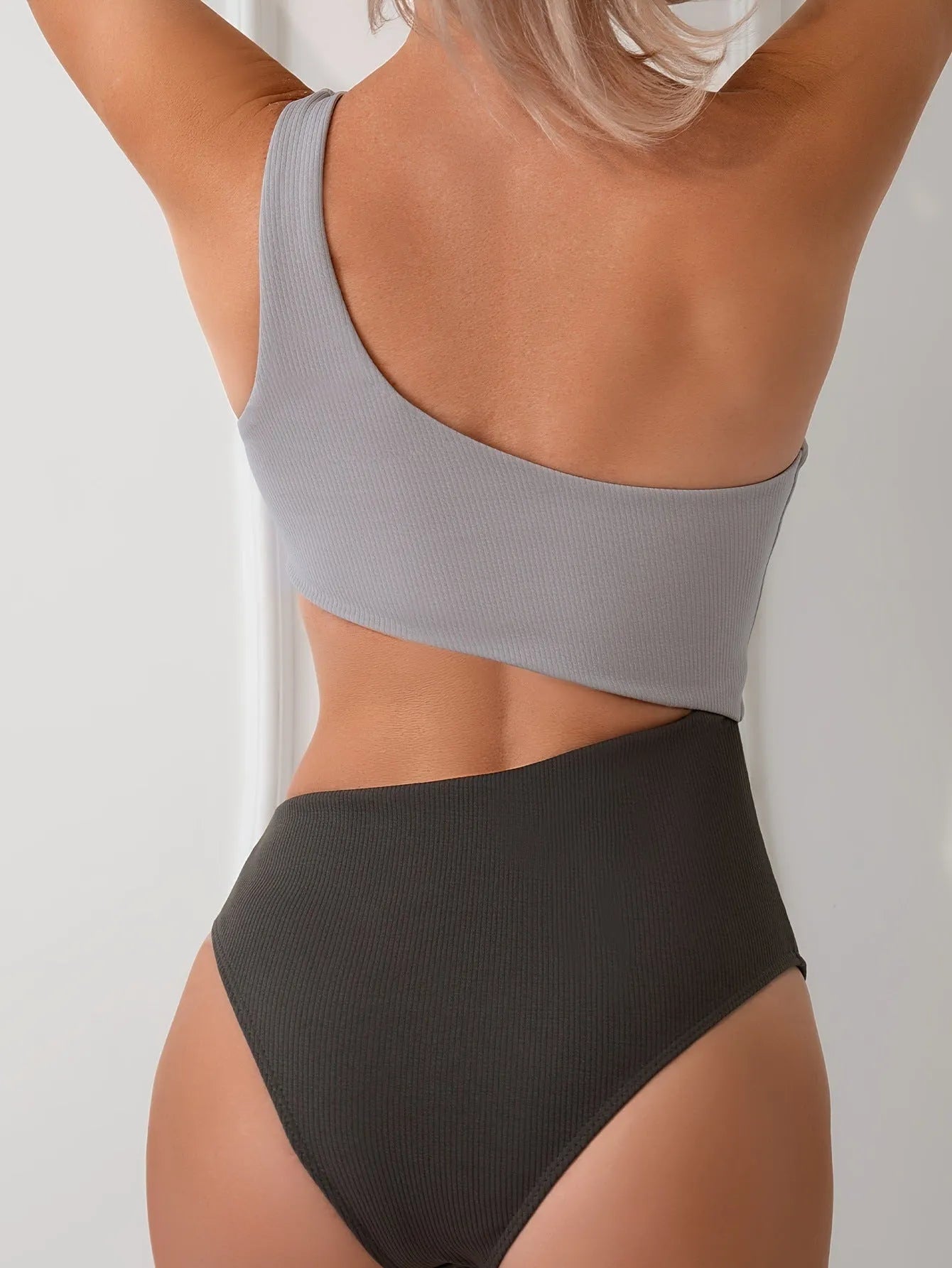 Light gray one-shoulder one-piece swimsuit on a white background.