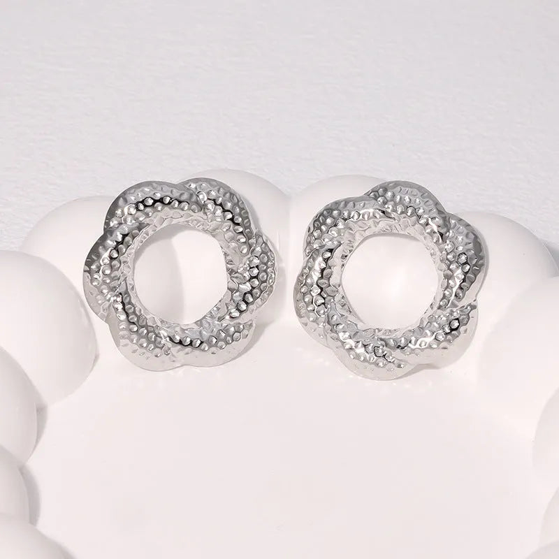 Stainless steel round stud earrings in gold and steel colours on a neutral background