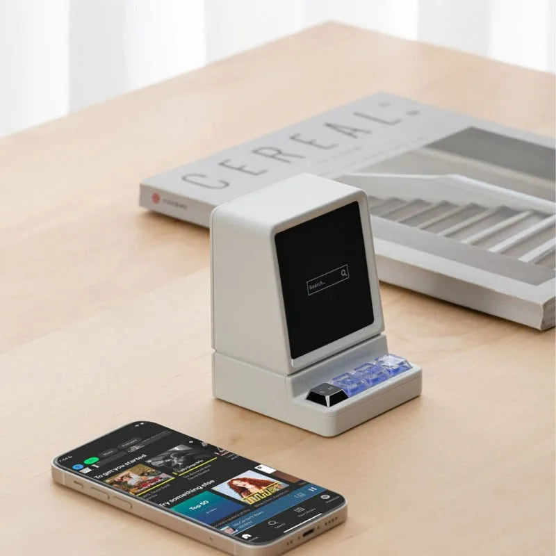 Light grey portable Bluetooth speaker shaped like a classic computer on a desk