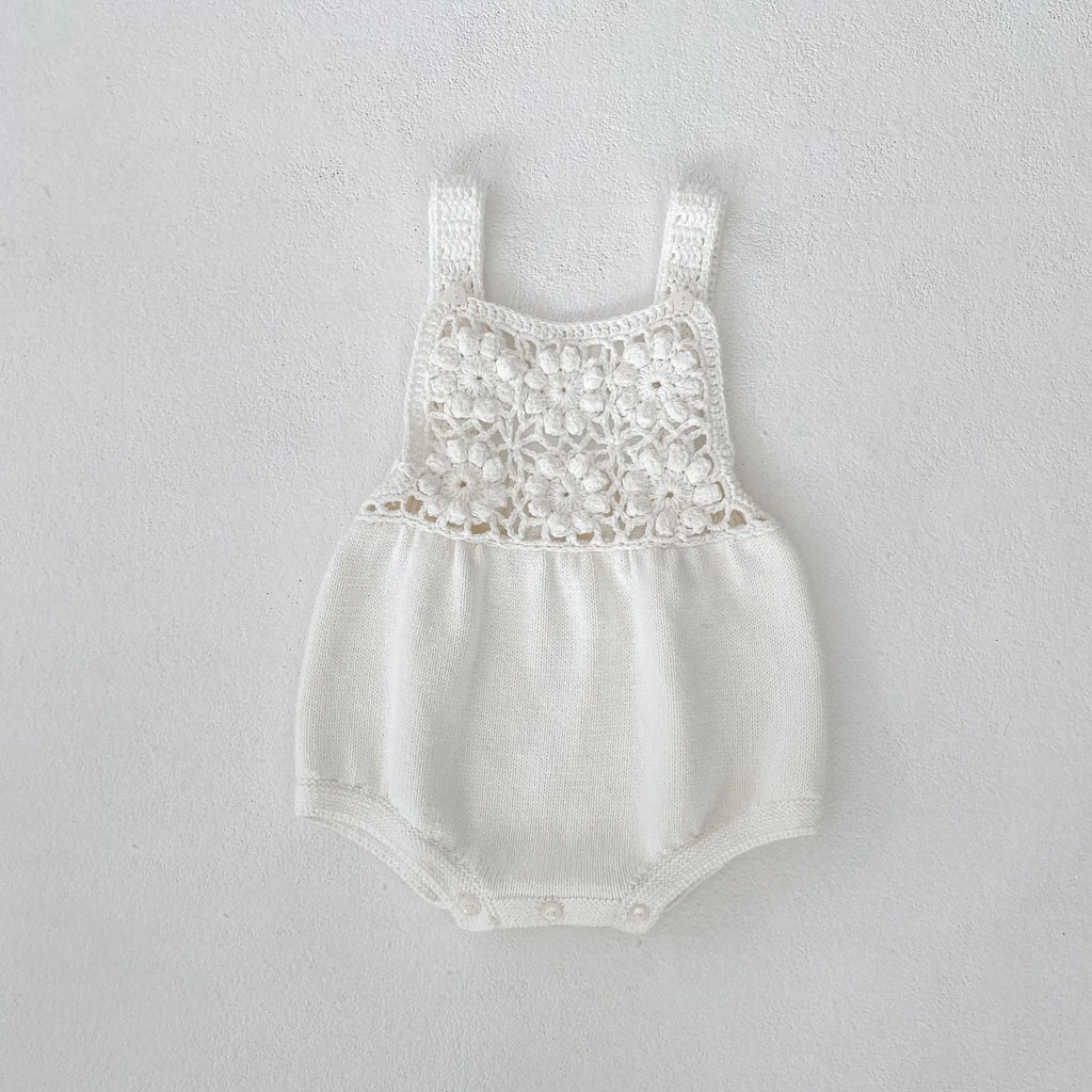 Beige baby romper with flower cutout strap and matching hat on a baby girl