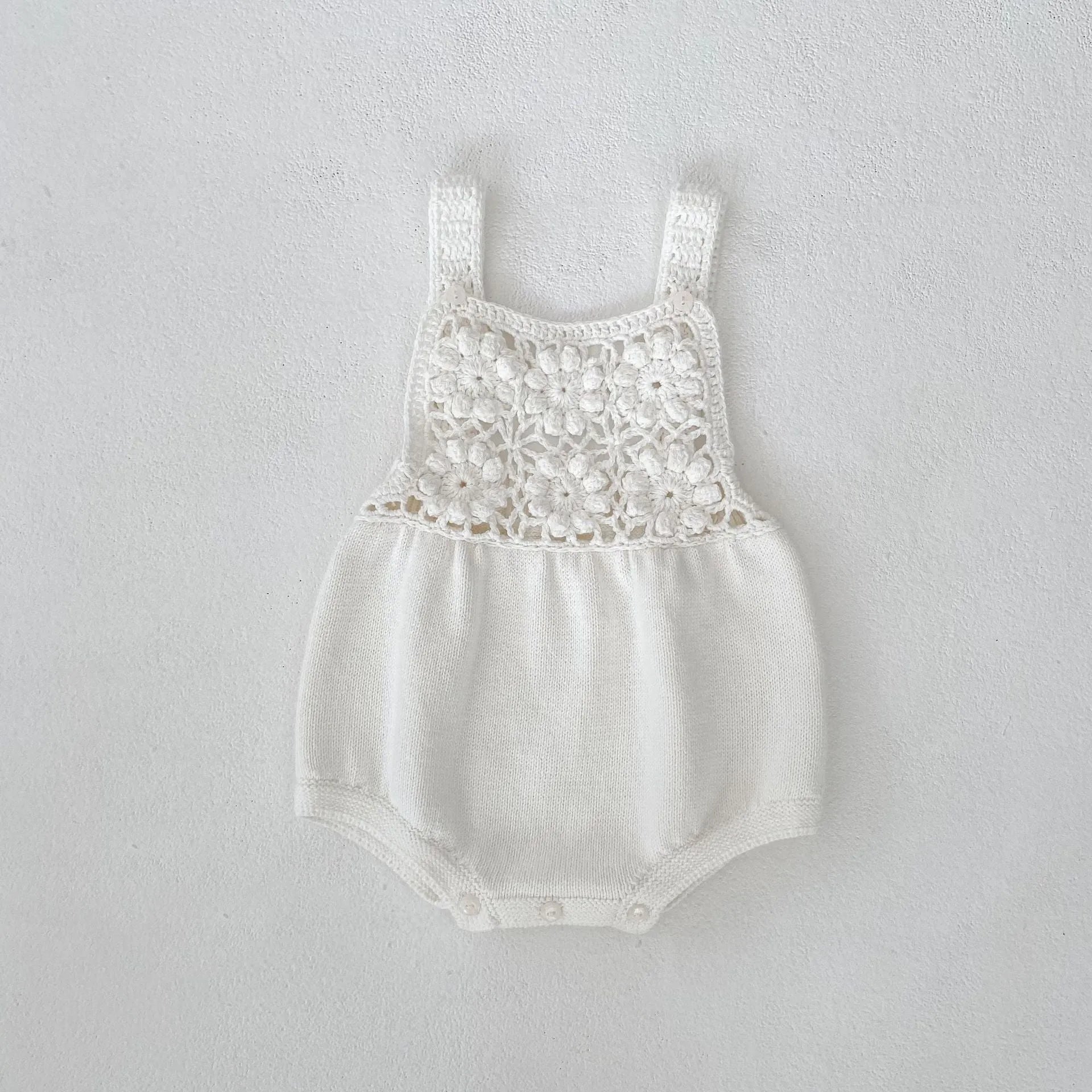 Beige baby romper with flower cutout strap and matching hat on a baby girl