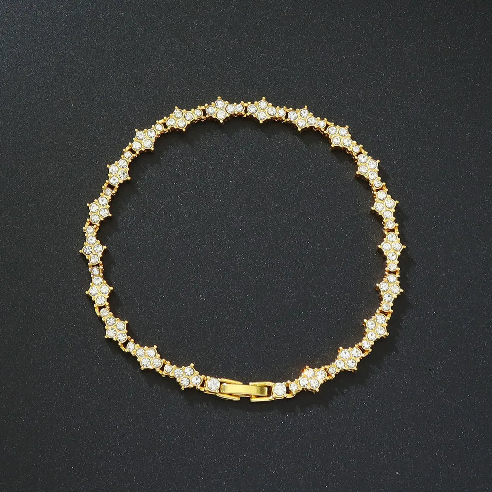Flower-shaped cross tennis chain bracelet in gold alloy on white background showing diamond and geometric detailing