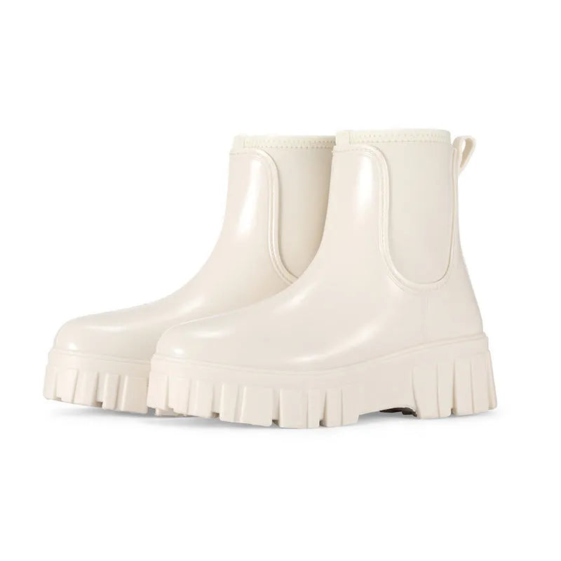 Creamy-white low tube PVC rain boot with non-slip sole on a wet surface.