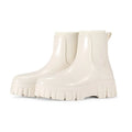 Creamy-white low tube PVC rain boot with non-slip sole on a wet surface.