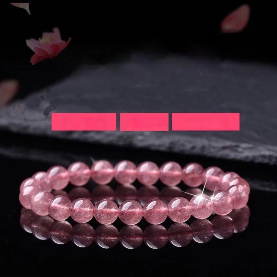 A women's bracelet with round, polished strawberry quartz crystal beads in pinkish-red tones.