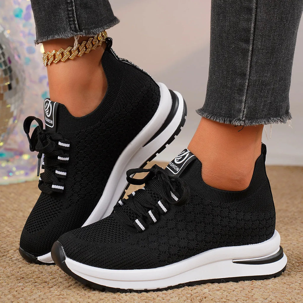 Women's black lace-up mesh sneakers with a flat rubber sole and round toe on a white background.