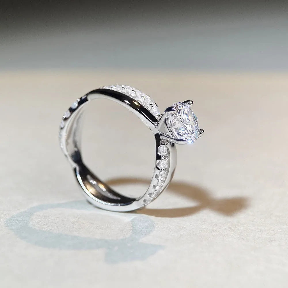 Geometric silver ring with a 1 karat moissanite in a four-claw setting, showing twisted band and cross design.