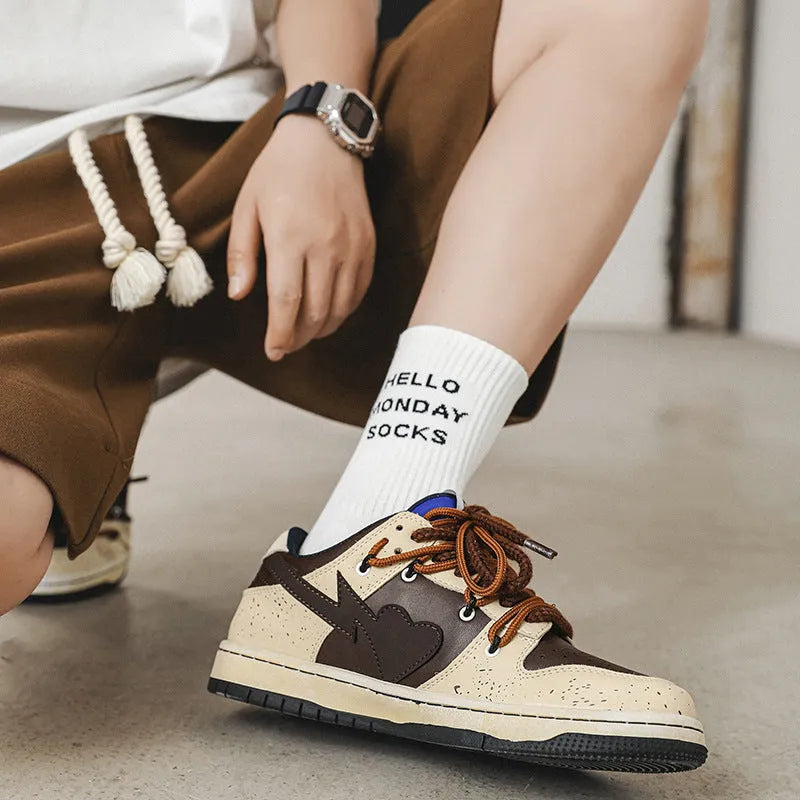 Brown low-top unisex casual sneakers with leather stitching, rubber sole, and front lace-up