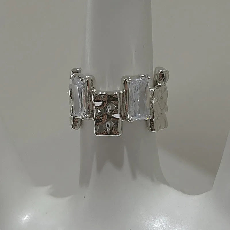 Silver plated open ring with a cross design and zircon gemstones in a geometric shape.