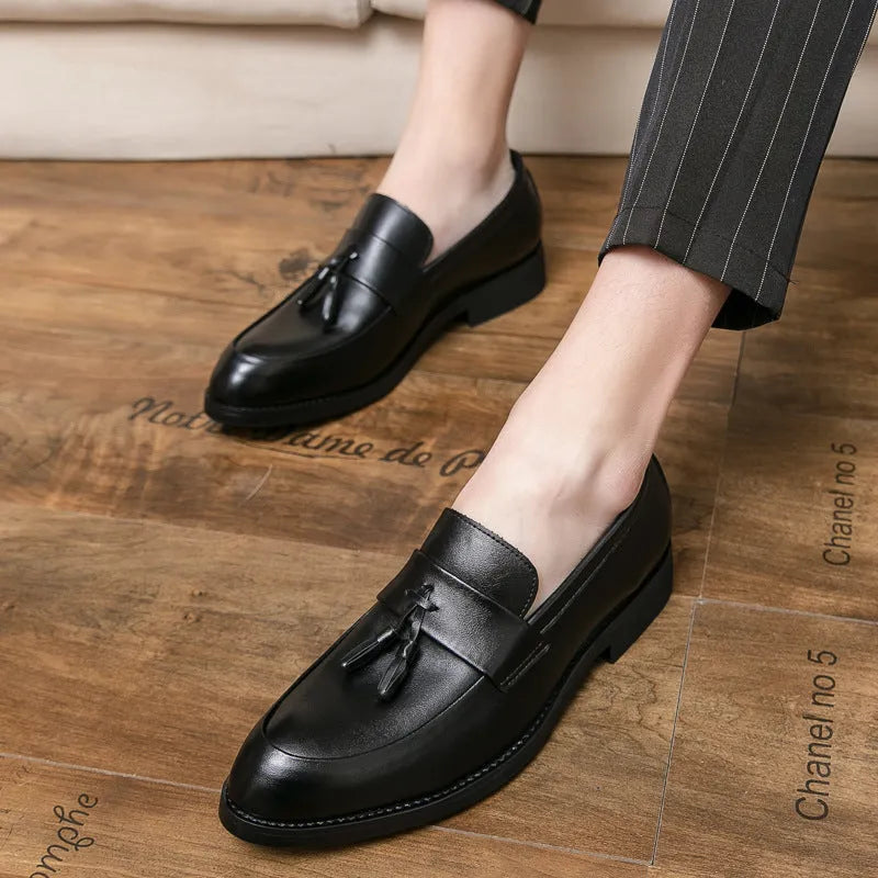 Men's black and brown slip-on business casual shoes with tassel detail and rubber sole.