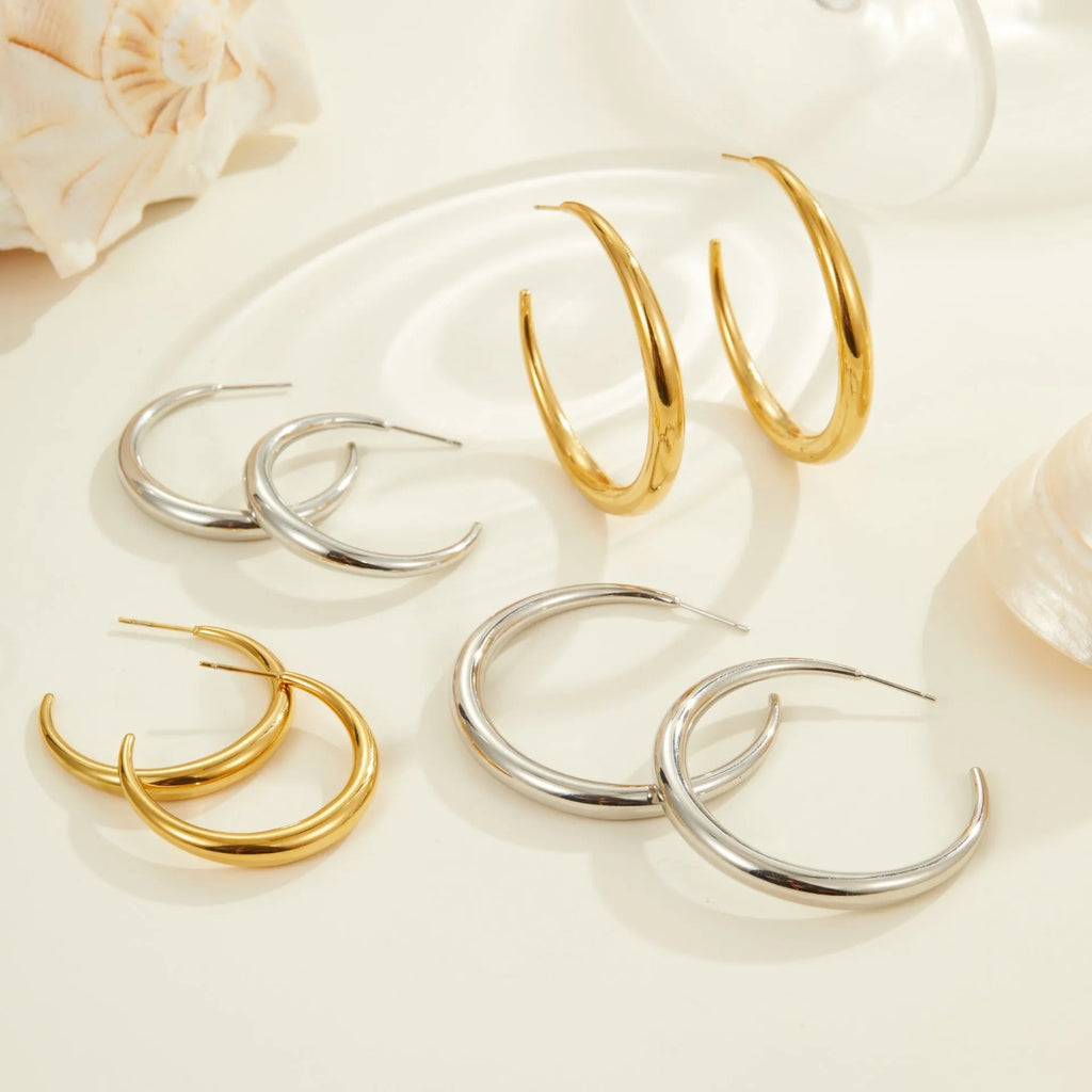 Simple round titanium steel hoop earrings for women in gold and steel finishes, shown in small and large sizes.