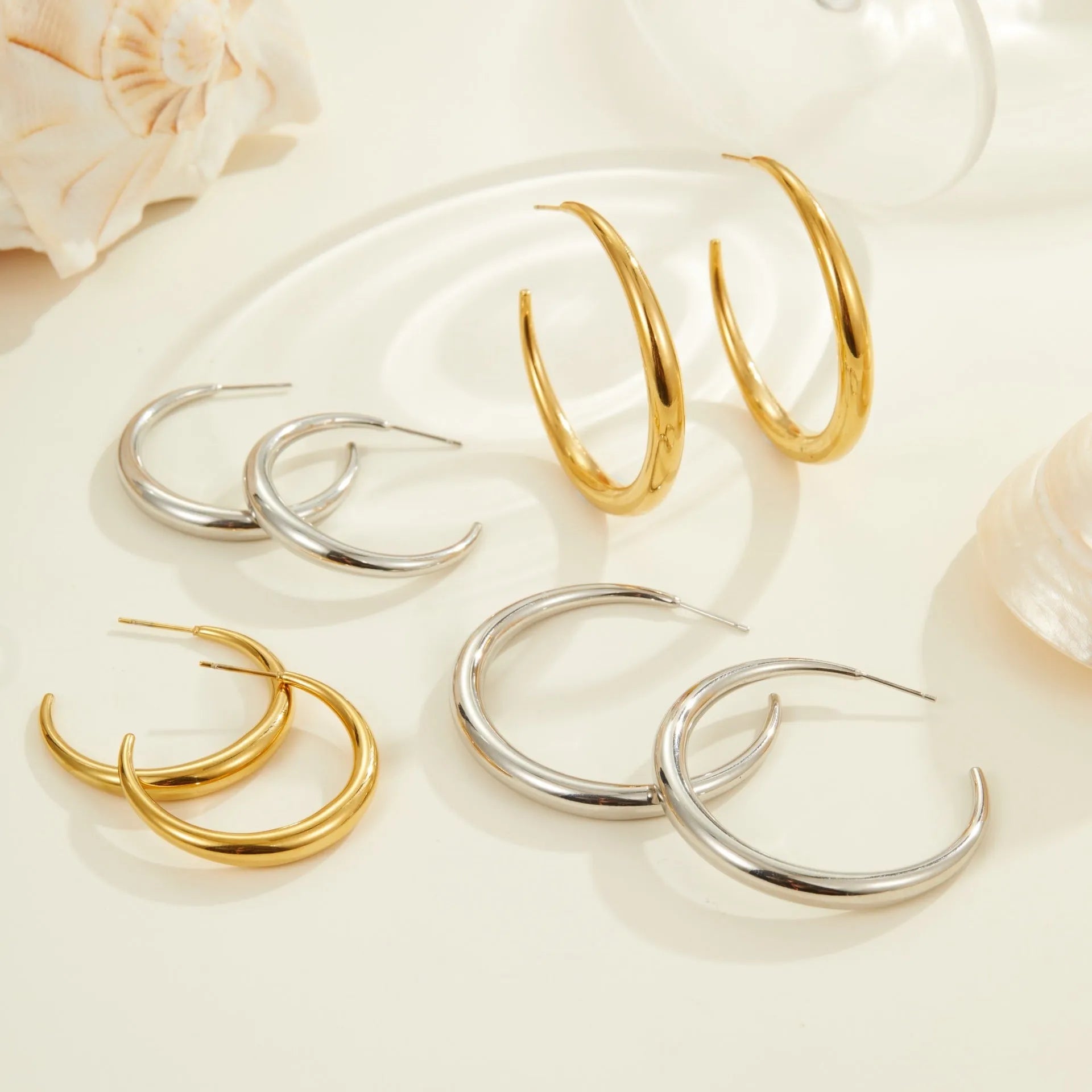 Simple round titanium steel hoop earrings for women in gold and steel finishes, shown in small and large sizes.