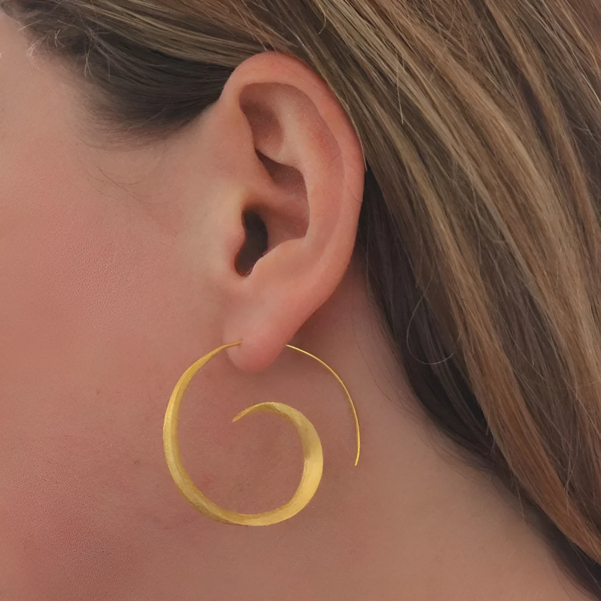 Gold alloy geometric round spiral leaf ear studs with electroplated finish on white background